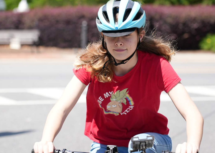 Happy girl putting on a bike helmet