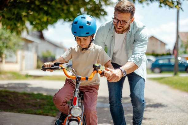 Loving Father Help His Cute Little to Son Ride a Bicycle, Wearing a bike helmet