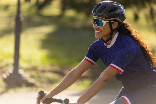 Young multiracial woman riding bicycle through countryside on sunny day. bike helmet