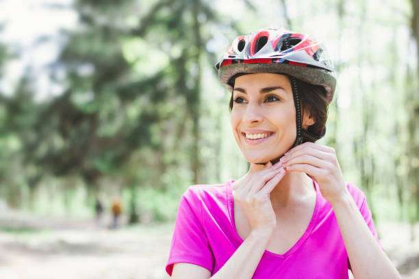 Beautiful and young African American woman riding, wearing a bike helmet