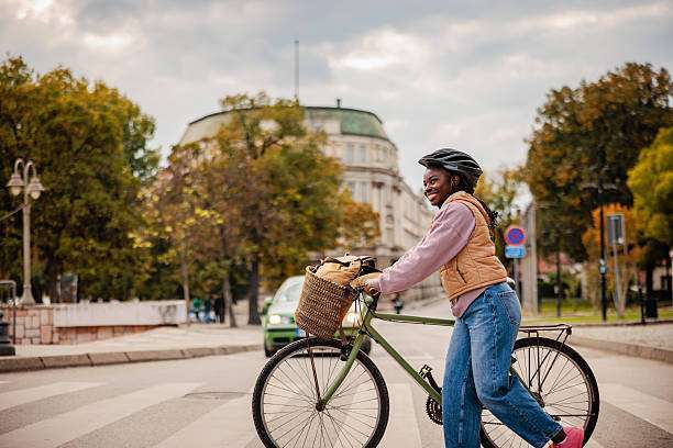 Beautiful and young African American woman riding, wearing a bike helmet