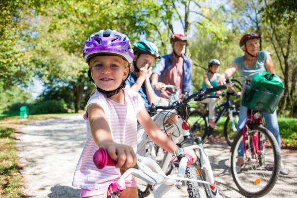 Happy girl in purple bike helmet ready for a family bike ride.