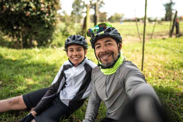 Man and boy smile, wearing bike helmet and cycling gear.