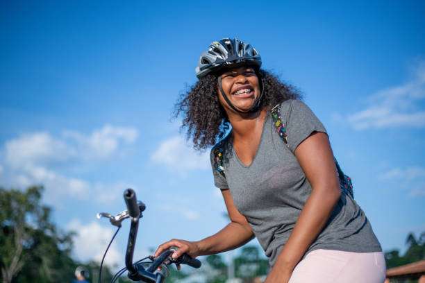 A mother is helping her daughter put on a bike helmet for safety