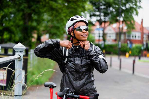 She is putting her bike helmet on and fastening it.