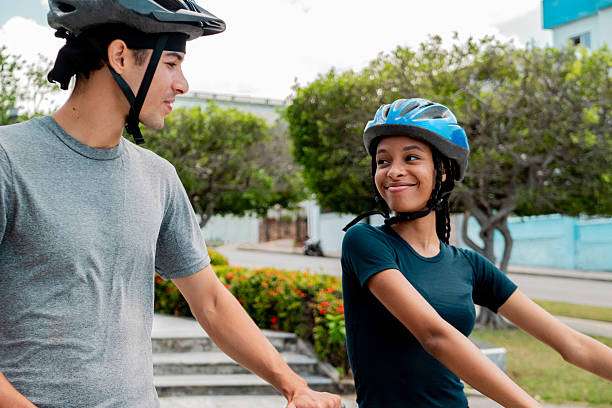 Two smiling young cyclists wearing bike helmets, enjoying a sunny day outdoors.