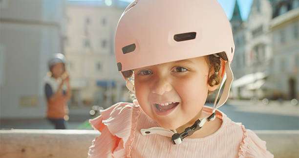 Happy child wearing pink bike helmet outdoors.