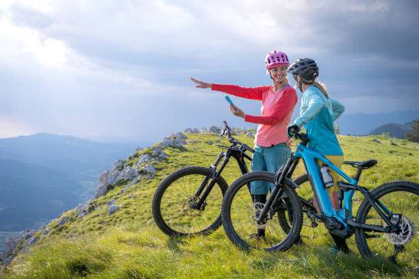 Two cyclists in bike helmets enjoying mountain views with e-bike.