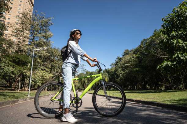 Woman with bike helmet smiling and enjoying a ride on a sunny day.