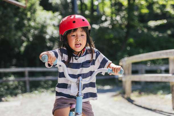 Young child in red bike helmet riding a bicycle with focus.