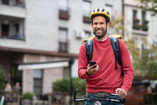 Delivery man wearing bike helmet and backpack, holding phone