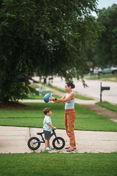 boy wearing a bike helmet rides a scooter in the driveway