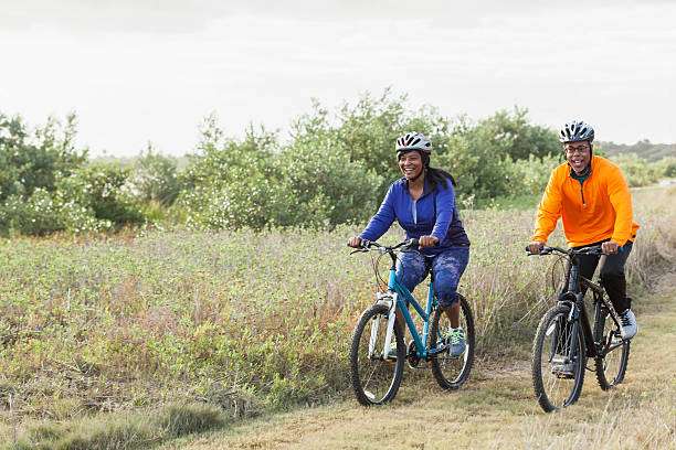 Couple cycling together in nature, both wearing bike helmets.