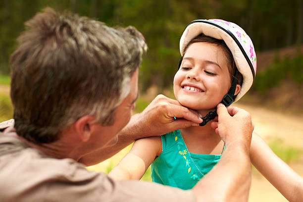 Shot of a father adjusting his daughter's helmet