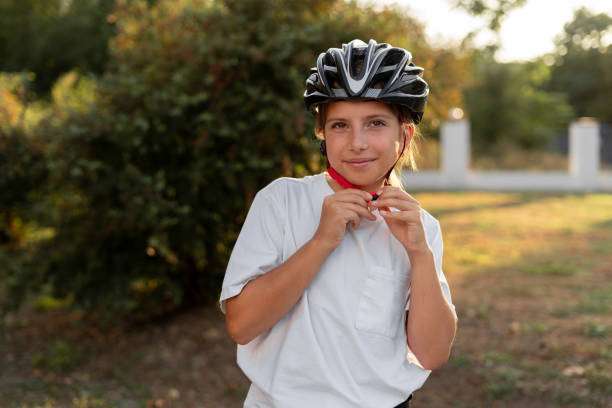 Biker girl putting on a protective bike helmet
