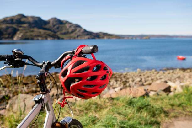 Red bike helmet hanging on bicycle handlebar by the ocean.