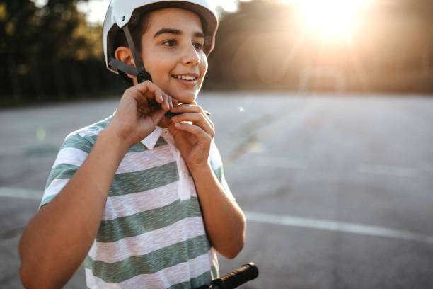 Boy adjusting his white bike helmet with a happy expression.